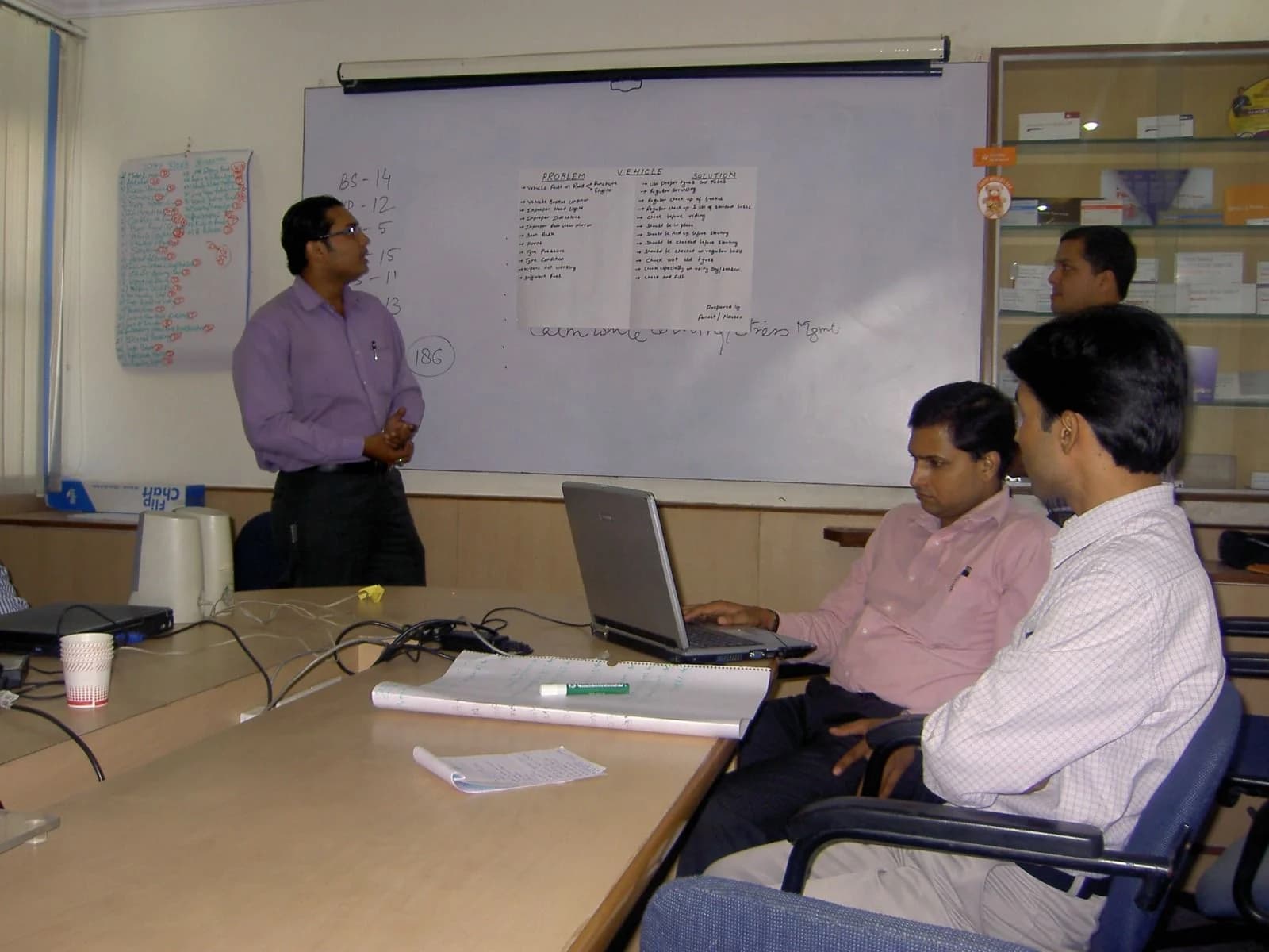 A facilitator at the whiteboard with participants at laptops